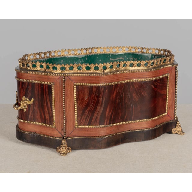 A late 19th century French Napoleon III marquetry jardinière with inlaid veneers of burled walnut and mahogany. Bronze-...