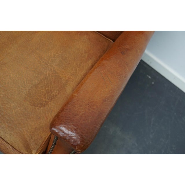 This leather club chair comes from France and was made circa 1940s. It is upholstered with cognac-colored leather and...