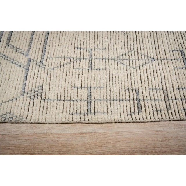 This hand knotted pile rug features a primary color palette of ivory, beige, cream, and white. Crafted from natural wool,...