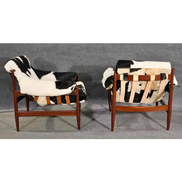 Pair of vintage arm chairs with hide seats on leather straps. Great mid-century design with black and white flair. Please...