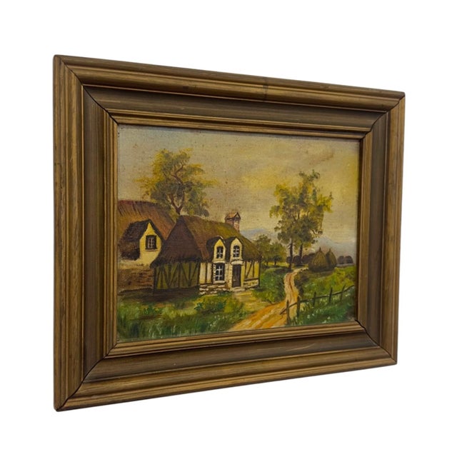 This vintage unsigned oil painting on board depicts an idyllic European country landscape featuring thatched-roof cottages...