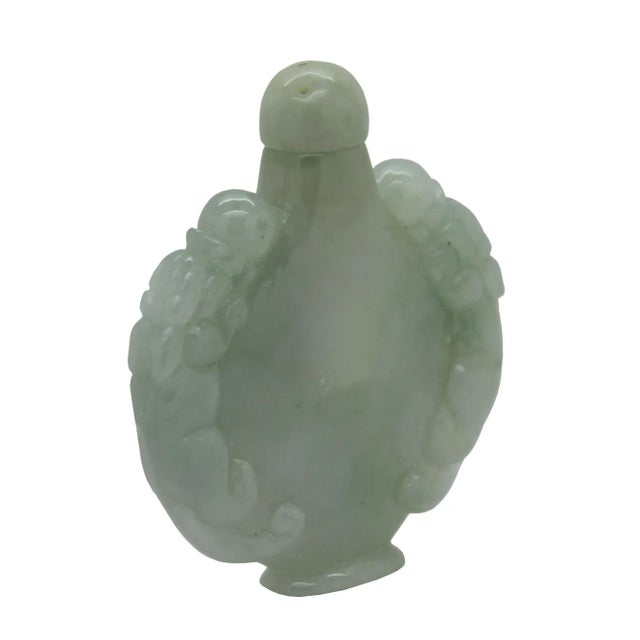This beautiful snuff bottle is carved from natural untreated jade, the motif of this small bottle is a foo dog chasing a...