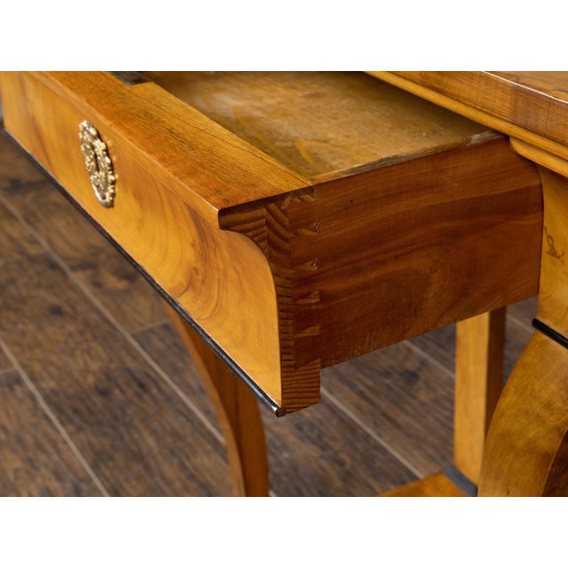 An Austrian Biedermeier period walnut console table from the 19th century, with single drawer, scrolling legs, lion paw...