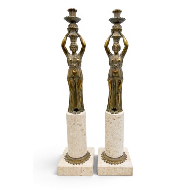 A pair of Neoclassical candlesticks. The figures are modeled, showcasing flowing robes, recalling the form of...