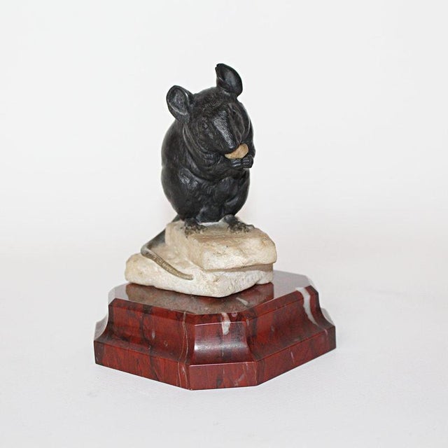 A carved mouse feasting while seated on pieces of cheese, carved from one piece of alabaster. Set over a red marble...