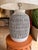 This contemporary table lamp features a textured ceramic base in soft white and charcoal gray, creating a striking yet...