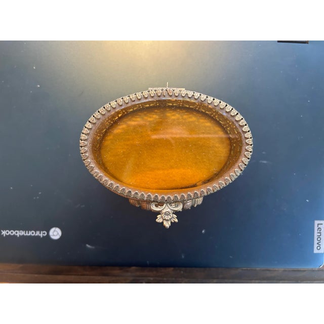 Vintage Hollywood Regency oval metal and glass filigree box with a seashell motif on front and claw feet. Little gold...