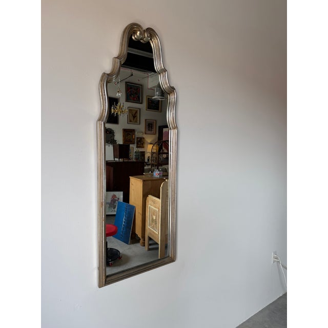 An elegant 1970s Hollywood Regency wall mirror by Bassett Furniture, featuring a gracefully sculpted wood frame with a...