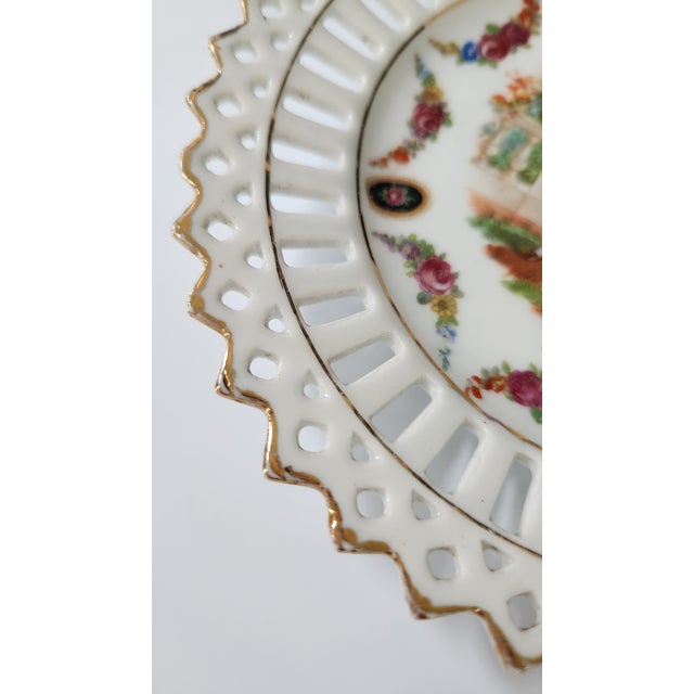 Charming set of two vintage German porcelain plates featuring romantic courting couple scenes framed by colorful floral...