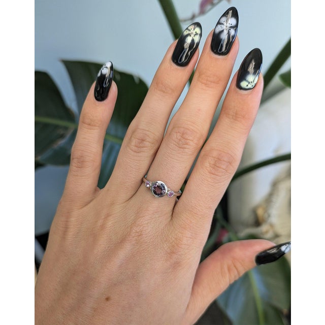 A natural purple spinel sits at the center of this solid 14K white gold ring, framed by two purple sapphire accents for a...