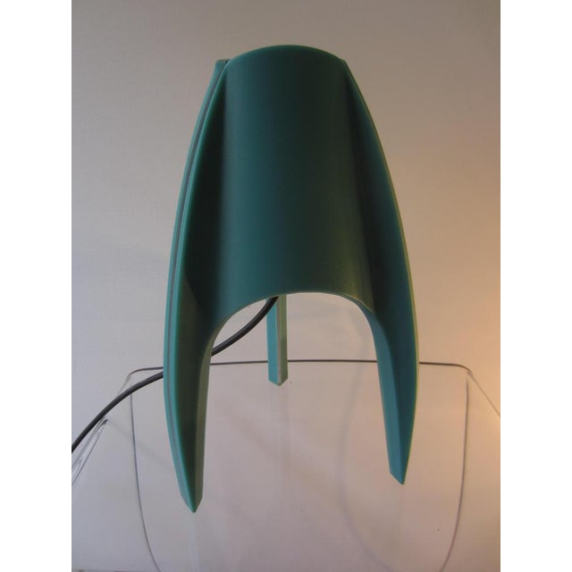 Tripod table lamp Arcadia made of plastic in turquoise green with transparent stripes through which the light shines....