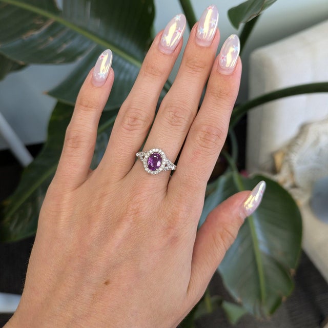 A natural purple sapphire glows at the heart of this oval ring, wrapped in a brilliant halo of diamonds and set in solid...