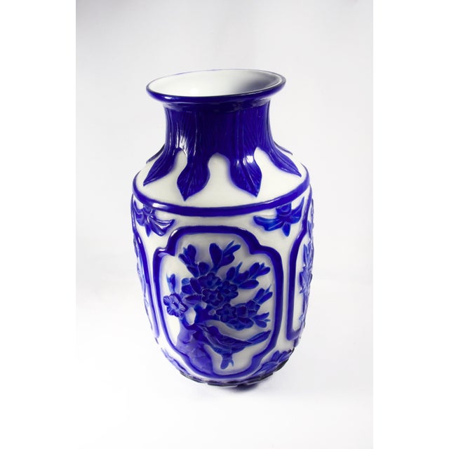 Milk white glass Peking vase with carved royal blue overlay. Design consists of four framed views of flora and birds. A...