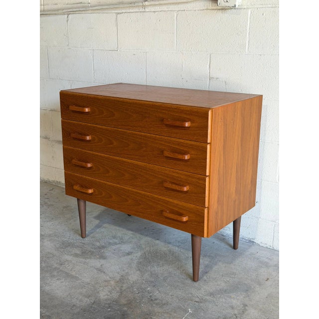 This sleek piece features four spacious drawers set above tapered legs. Smooth horizontal carved pulls highlight the clean...