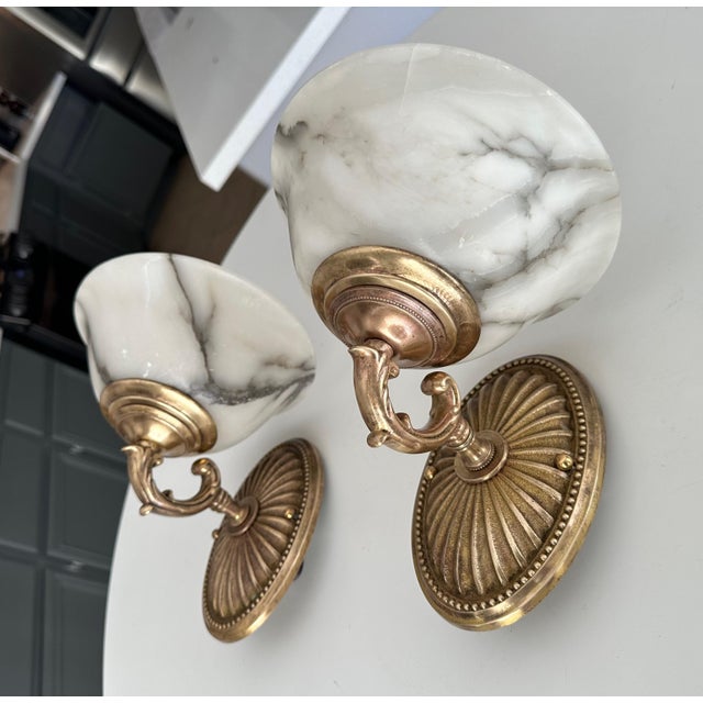 Pair brass brass wall sconces with alabaster globe shades and sunburst motif backplates. Newly wired for US installation....