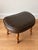 Mid-century modern kidney-shaped footstool featuring a rich brown leather cushion with beautiful patina and turned wooden...