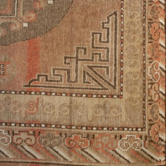 A 19th century Central Asian Samarghand carpet with three central medallions on a field of muted red surrounded by a...
