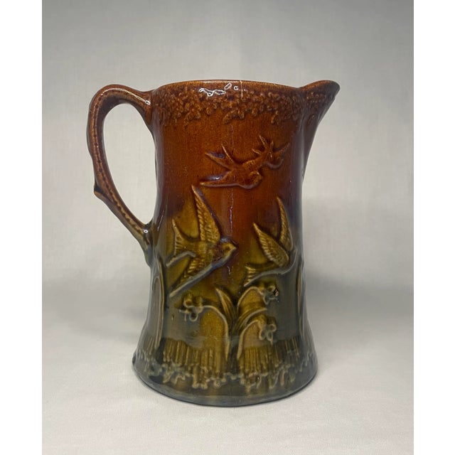 This vintage crackled glazed pitcher depicts two scenes; a pair of lovebirds, and a family of birds on the opposite side....