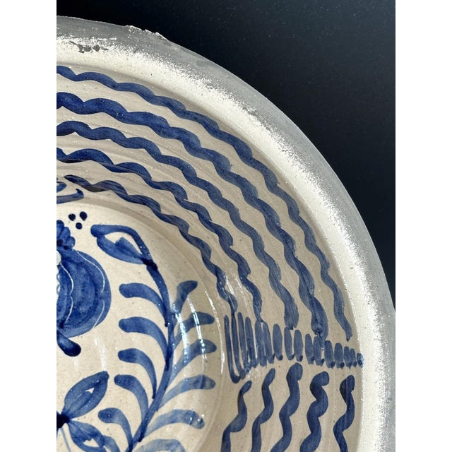 A traditional Fajalauza ceramic bowl from Granada, hand-painted in vibrant cobalt blue with a central motif of a stylized...