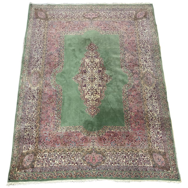 A finely hand-knotted vintage Persian Kerman area rug featuring a distinctive open green field centered by an elongated...