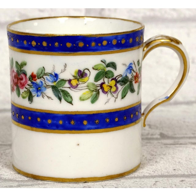 Soft Porcelain With a white background, the set features a polychrome decoration of floral garlands running between two...
