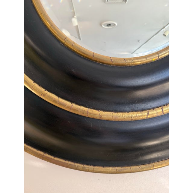 Striking black and gilt round mirror adds a bold, architectural element to any space with dramatic concentric frame, hand-...