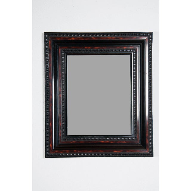 Red Tortoise framed mirror with carved inner edge. Beaded details around edge of frame. The inner inset has beading as...