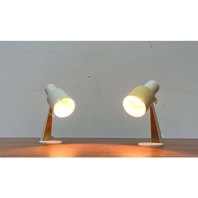 Small mid-century French table lamps. An elegant design in white and brass with colored accents. The lamps consist of a...