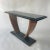 Unique French Art Deco console table rendered in black painted wood supported by a curved walnut base and a black glass...