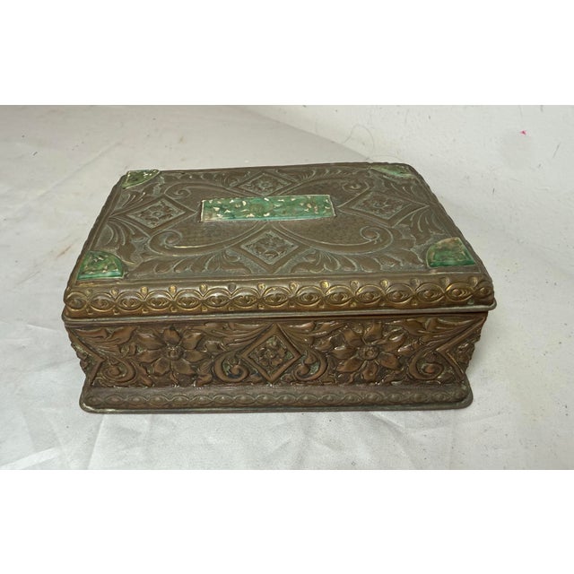 This antique 19th-century hand-tooled copper cigarette box from China features intricate carvings and inlays of green...
