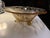 This is an amber-yellow vintage glass footed bowl with an etched floral and scrolling vine design, likely a Fostoria...