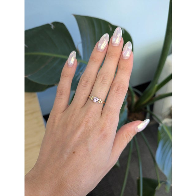 A natural purple spinel from Madagascar takes center stage in this round ring, encircled by sparkling diamonds in solid...