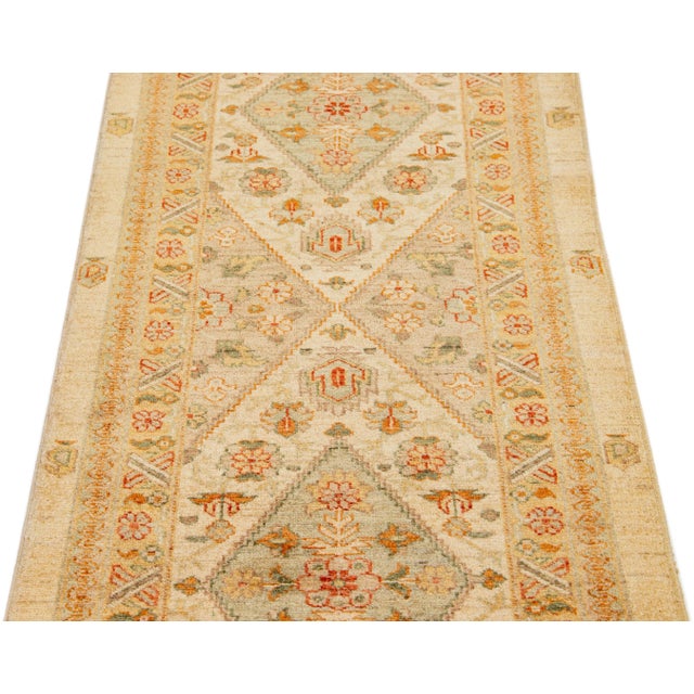 This contemporary hand-knotted wool runner from India is exquisitely designed with a beige field, adorned with a...