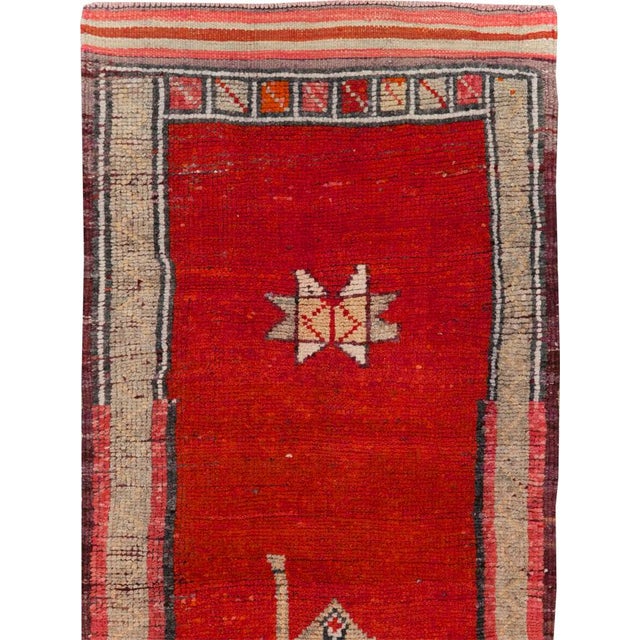 This mid-20th-century Turkish Anatolian runner presents a bold, sparsely ornamented composition centered on a rich red...