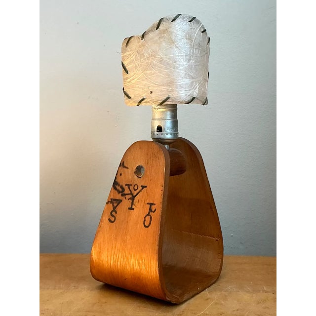 This vintage table lamp pairs a sculptural stirrup-form wood base with metal hardware, reflecting the organic, hand-...