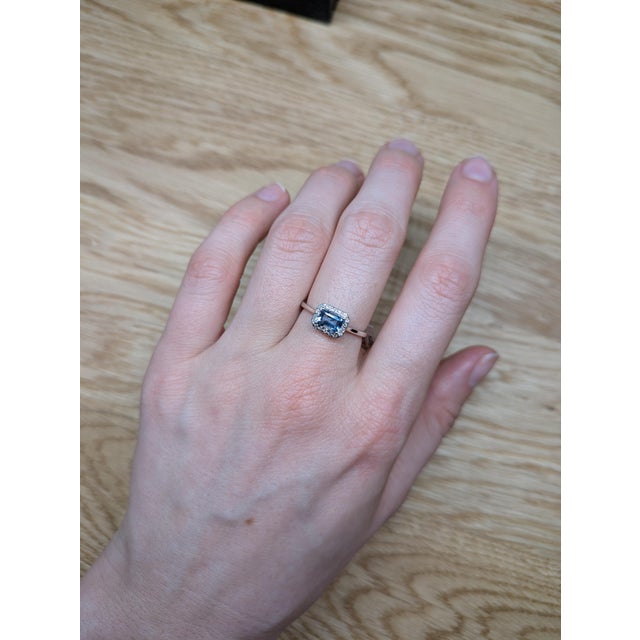 This dainty east-west ring features a 0.46 carat emerald-cut aquamarine set horizontally in 14k real white gold. Framed by...