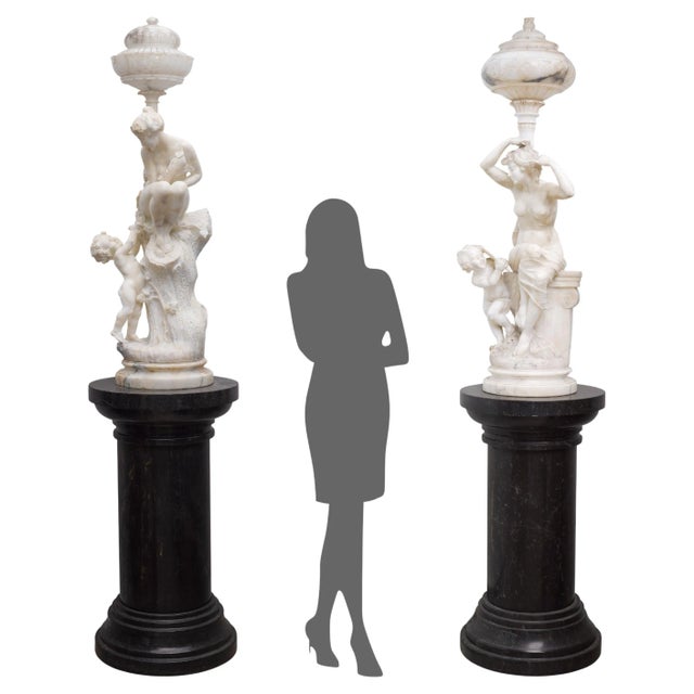 An exceptional and highly decorative pair of antique Italian hand-carved alabaster figural torchiere lamps, each depicting...