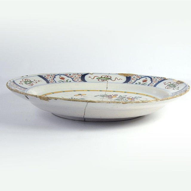 A unique, large, and highly decorative Dutch Delft plate. Crafted from hand-painted faience, it comes from the Dutch Delft...