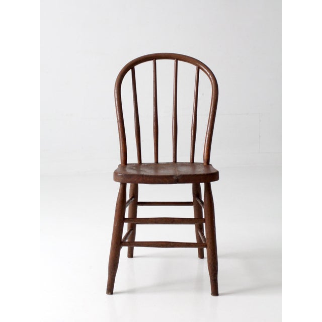 This antique late 19th-century American Windsor bow back chair features a continuous bentwood crest rail, five spindles, a...