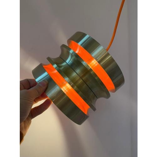 Scandinavian lighting magic: This pendant lamp in warm gold and fiery orange, designed by Carl Thore, perfectly embodies...