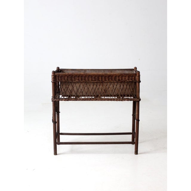This is an antique wicker plant stand. The brown woven stand features a woven shelf and top basket with a removable...