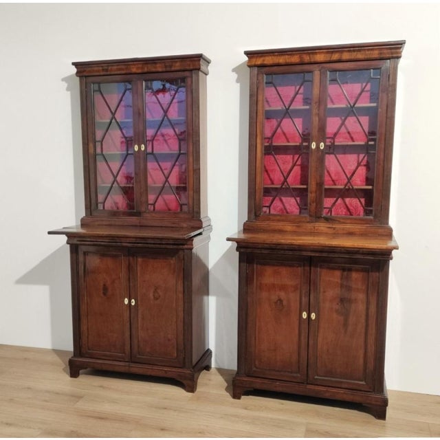 A rare pair of small bookcases, made of walnut and featuring a pull-out shelf. The upper glass section features original...