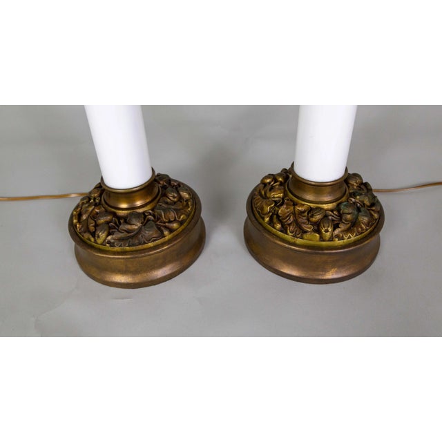 A striking pair of sizable table lamps with milk glass columns on bronze-tinted grape leaf bases. They are made by Paul...