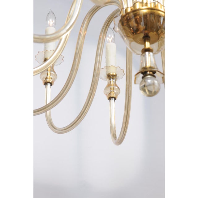 This is a beautifully executed Venetian glass chandelier with gently curved arms and refined brass detailing. The piece...
