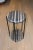 Two rounds of black and gray travertine rest in between five legs of black steel. Dimensions: 14" W X 24" H X 14" D...