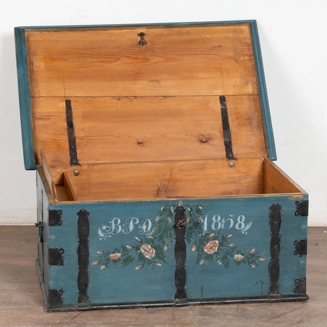 The colorful blue paint is all original on this beautiful flat top trunk. Flowers were a traditional embellishment as seen...