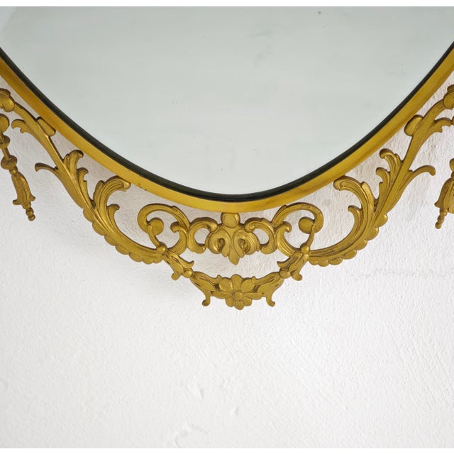 A refined, generously sized oval wall mirror in the Neoclassical/Adam style, featuring a gilded frame with finely carved...