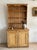 An English pine stepback hutch with an open plate rack above, the top edged by a scalloped apron, over a base of twin...