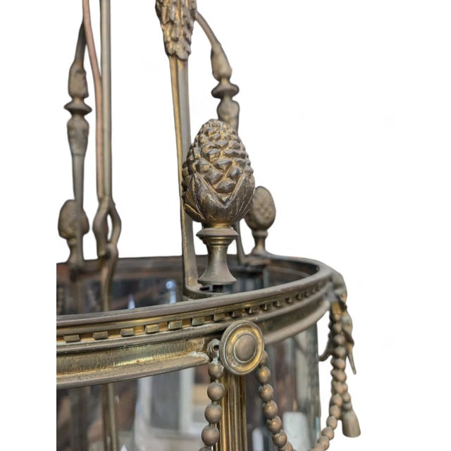 Petit Trianon style circular brass hanging lantern. The lantern top is adorned with Pineapples and leaves. The top of the...
