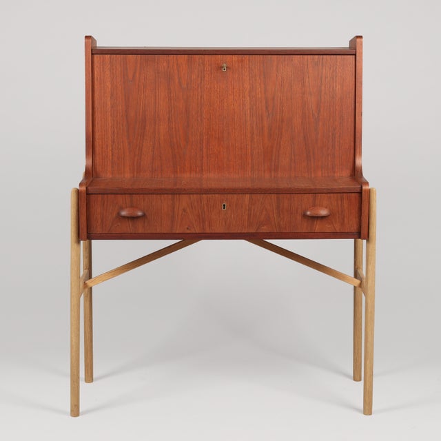 Danish secretary desk, circa 1960, in solid and veneered teak with an oak frame. The desk features a lower drawer and...